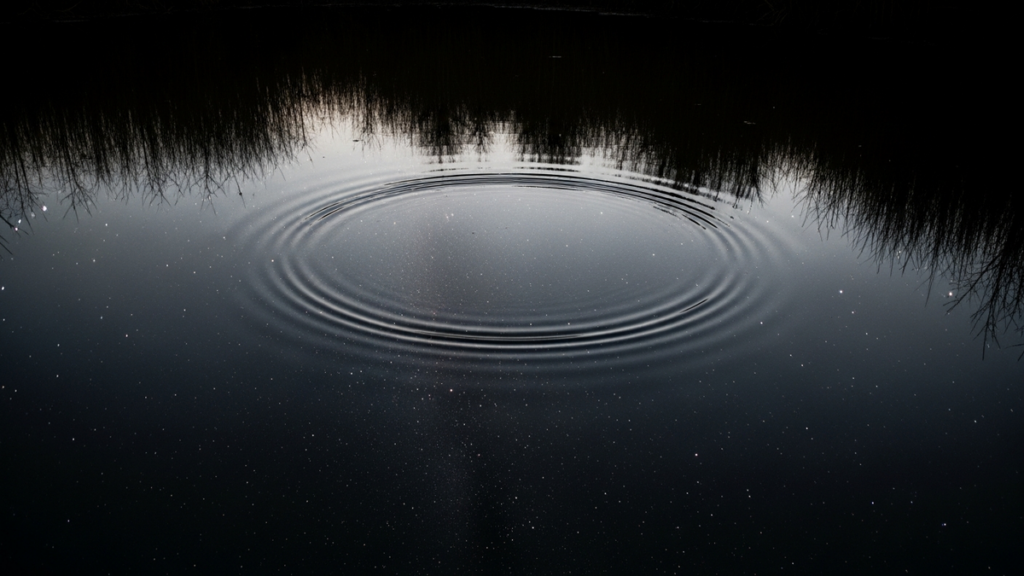 A still dark pond at night reflecting a star-filled sky like a mirror, faint ripples spreading